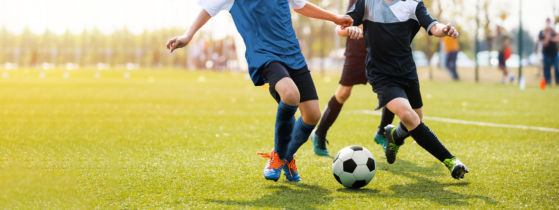 Two soccer players running and kicking a soccer ball.