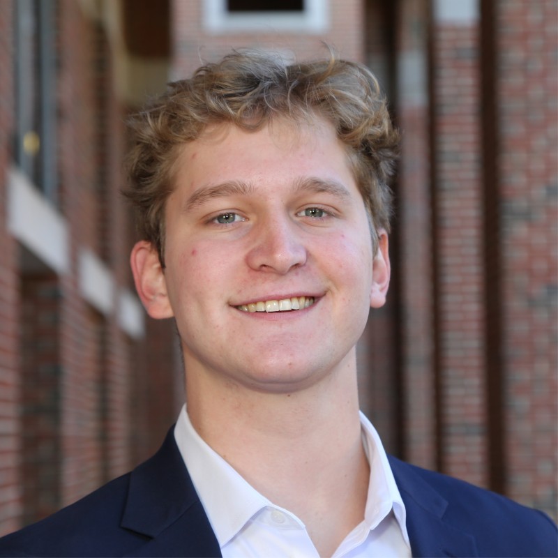 Portrait of Headshot of a young man standing against a brick building
