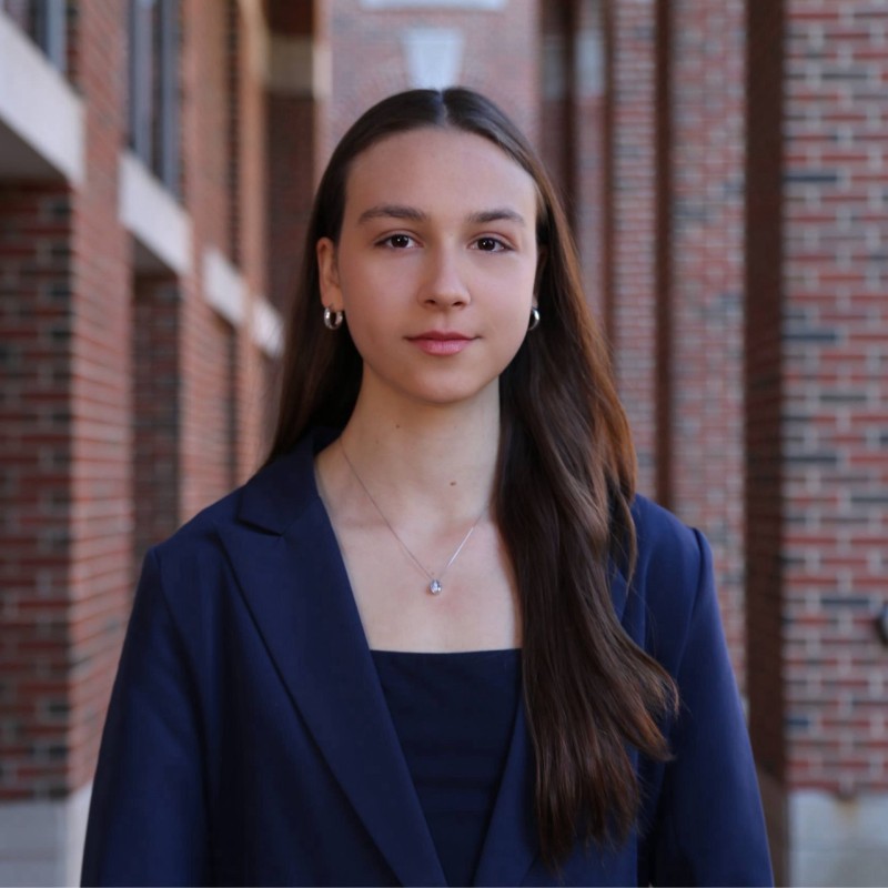 Portrait of Headshot of a young woman standing against a brick building