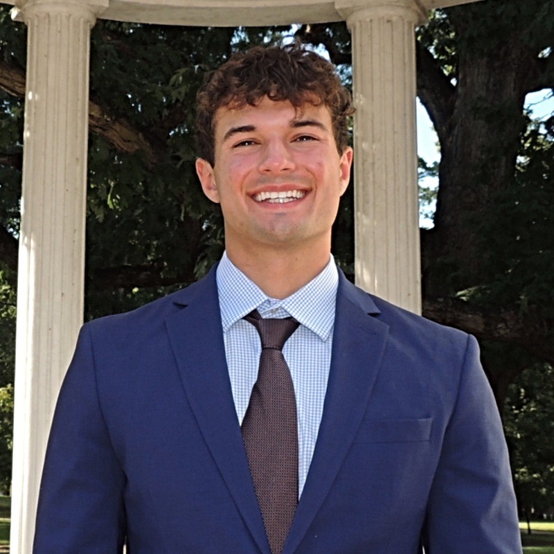 Portrait of Headshot of a young man in a suit at the Old Well at UNC-Chapel Hill.