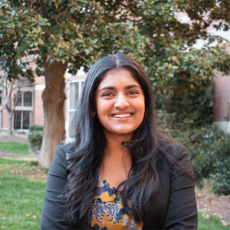 Portrait of Headshot of a young woman outside with foliage in the background