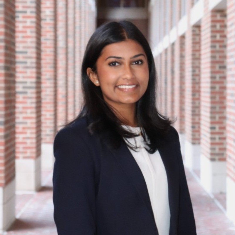 Portrait of Headshot of a young woman in a black blazer standing against a brick building