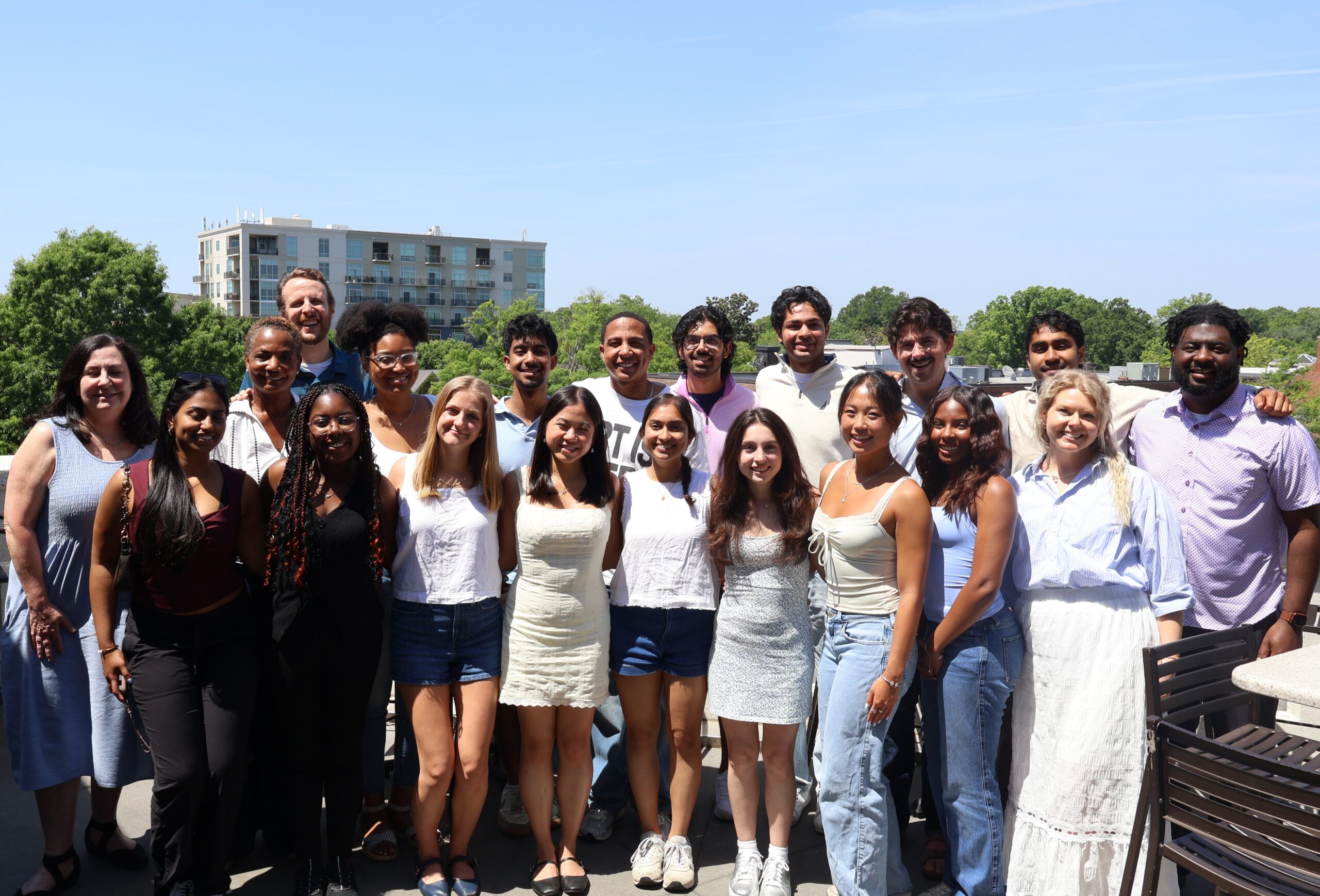 Two rows of smiling UNC seniors and LHS staff on a sunny patio above Franklin Street in Chapel Hill, NC
