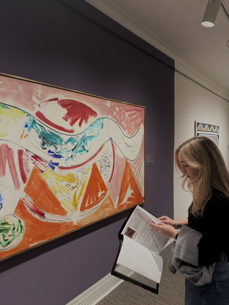Scholar reading about a piece of colorful, shape-filled art hanging at the Ackland Art Museum